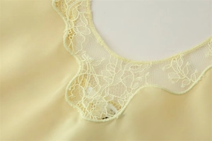 Détail du col en V en dentelle élégante et texture satinée jaune clair sur le haut