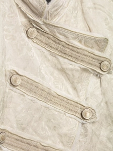 Close-up of beige jacquard jacket fabric with metallic embossed buttons and frayed edges