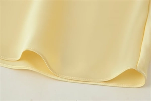 Vue détaillée de l'ourlet en satin crème avec coutures fines et texture douce et soyeuse