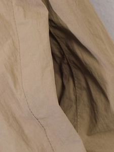Detail of side pocket on khaki long sleeve zip-up jacket with textured fabric