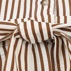 Detail of seersucker striped jumpsuit with waist bow tie and amber button