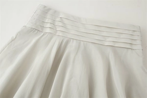 Detail shot of multi-layered pleated waist design on elegant silk texture skirt