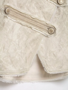 Detail of cream jacquard jacket featuring vintage gold crown crest buttons and frayed edges