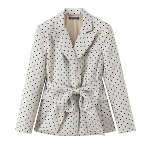 Dettaglio del blazer a pois con cintura a fiocco e tre bottoni su tessuto bianco