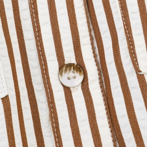 Macro shot of striped seersucker fabric detail and marble texture button on a romper