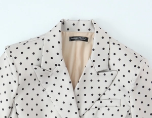 Dettaglio del rever e dell'etichetta del brand su un blazer da donna a pois
