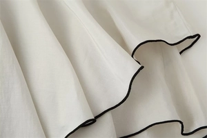 Close-up of white semi-transparent fabric with black piping detail and fine stitching