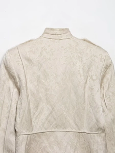 Detail of floral jacquard texture and stand collar on women's cream jacket coat