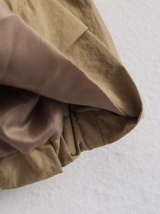Detail of khaki jacket showing elasticized hem design and smooth brown lining