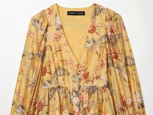 Detail of yellow floral dress showing deep V-neckline and elegant gold buttons