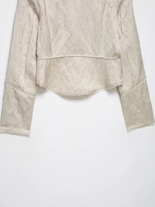 Close-up of the ivory floral jacquard fabric texture and curved hem on the jacket