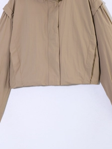 Detail of light khaki hooded jacket featuring windproof fabric and double-layered shoulder