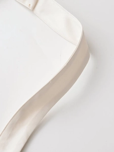 Detailed close-up of the fine stitching on the cream white halter neck dress fabric strap