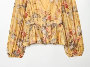 Detail of yellow floral V-neck peplum blouse with delicate buttons and lantern sleeves