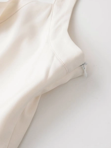 Detail of the high-quality twill fabric and invisible side zipper on a cream mini dress