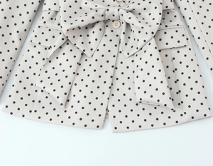 Dettaglio blazer a pois color albicocca con fiocco decorativo e tasche laterali con patta