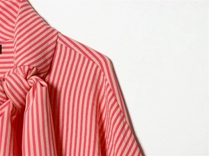 Detailed view of the pussy-bow neck and pink vertical stripes on a stylish cotton shirt