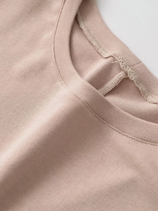 Detailed macro view of the crew neck collar and ribbed stitching on a pink knitted top