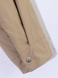Detail of khaki jacket cuff featuring high-quality windproof fabric and silver metal button