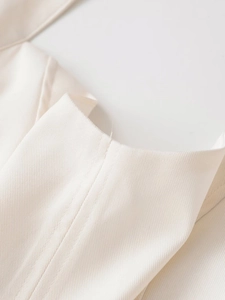 Detailed macro shot of fine twill fabric texture and neat stitching on a cream white dress