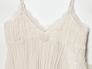 Detailed close-up of V-neckline with delicate eyelash lace trim on off-white fabric