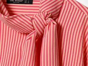 Close-up of pink striped shirt collar with tie-bow and ZEAL WOMAN brand label