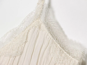 Close-up of ivory camisole featuring delicate eyelash lace trim and pleated fabric texture
