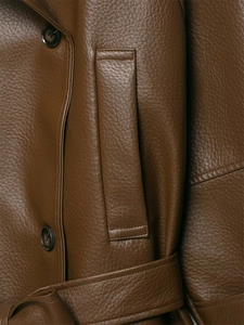 Detail view of dark brown pebbled faux leather texture with buttons and belt on a trench coat