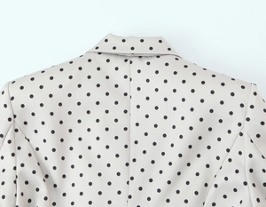Dettaglio del bavero e del retro del collo di un blazer bianco a pois da donna