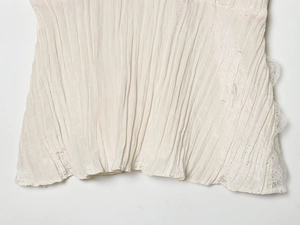 Close-up of pleated off-white fabric with delicate lace crochet edge detailing