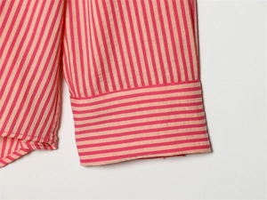 Close-up of pink and white striped shirt cuff with detailed stitching and woven texture
