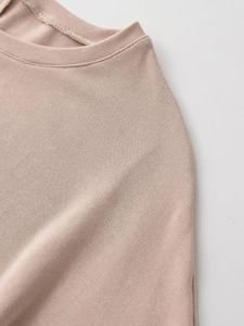 Detailed close-up of ribbed texture and high-quality stitching on a pink knit top
