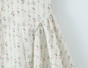 Detailaufnahme von cremefarbenem Blumenstoff mit rosa Blüten und gerafftem Saumdesign