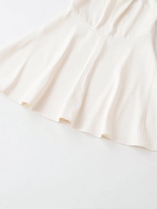 Detailed view of off-white sleeveless dress with stitching and umbrella pleat hemline