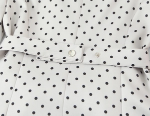 Dettaglio macro della cintura con bottoni in metallo su una giacca blazer a pois beige