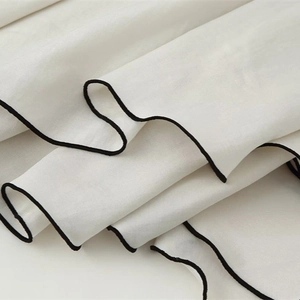 Fashionable white tiered skirt with elegant black contrast piping and flowing drapes