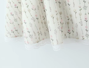 Detail des geblümten Saums mit zarter weißer Spitzenborte an einem Sommerkleid