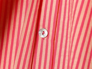 Detailed macro view of vibrant pink and orange vertical stripes with pearl button detail