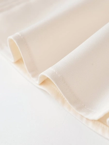 Detail shot of the cream halter dress showing fine fabric texture and neat stitching