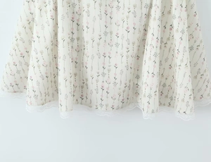 Nahaufnahme des Saums mit Blumenmuster und feiner weißer Spitze am Sommerkleid