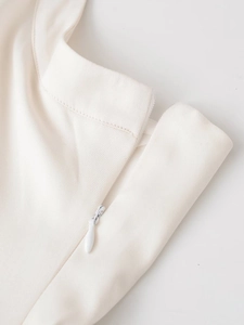 Detailed view of invisible side zipper on white halter dress with twill fabric texture