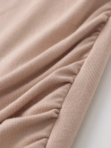 Close-up of peach ribbed knit fabric with delicate side ruching and soft texture detail