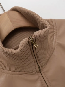 Detail shot of the stand-up collar with ribbed knit texture and gold metal zipper on jacket