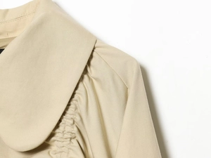 Macro shot of khaki trench coat collar with pleated shoulder detail and twill fabric texture