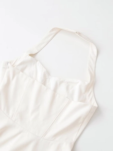 Detail of white halter neck dress featuring structured twill cotton and side zipper closure