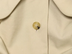 Close-up of the amber texture button and high-density twill cotton fabric on a beige trench coat