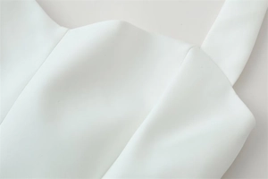 Detailed macro view of pure white sleeveless top showing neck stitching and strap connection