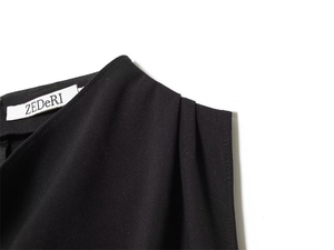Detail of shoulder pleats and neck label on a sleeveless black top with smooth texture