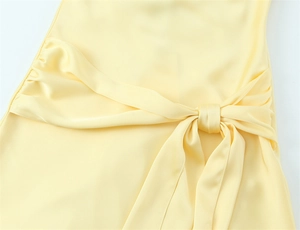 Dettaglio dell'abito in raso giallo chiaro con elegante fiocco e trama setosa