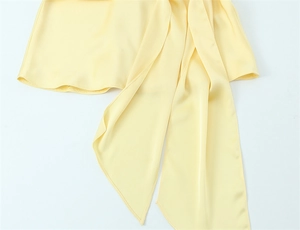 Dettaglio dell'abito in raso giallo chiaro con trama di seta e eleganti lacci lunghi